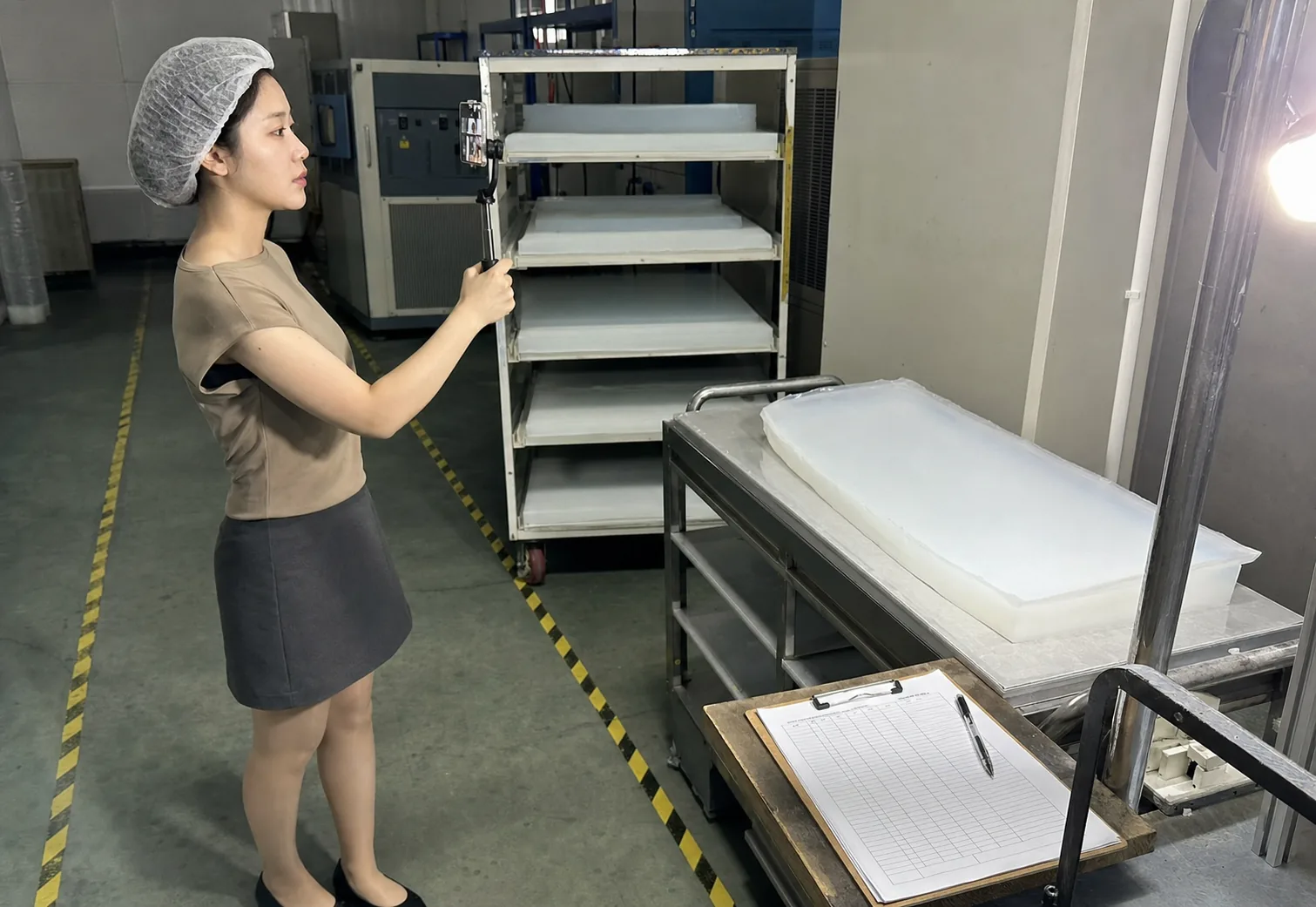 自媒体拍摄人员在气凝胶生产交接区用普通手机记录半成品、周转状态和工艺记录位置